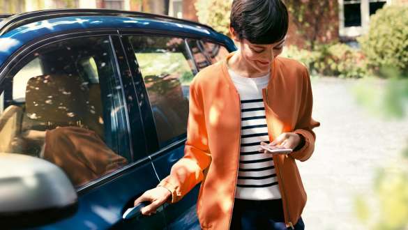 BMW Teleservices BMW Teleservices žena s pametnim telefonom pokraj BMW vrata