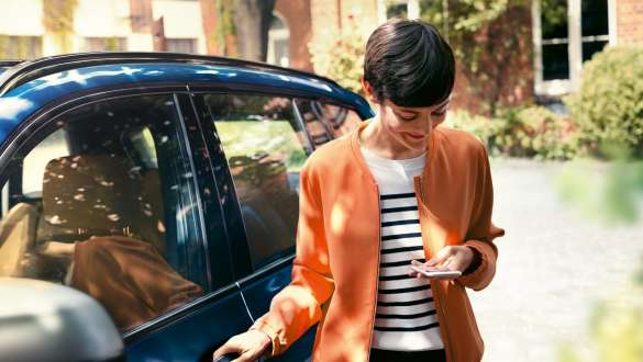 Žena s pametnim telefonom Žena izlazi iz BMW-a gledajući u pametni telefon