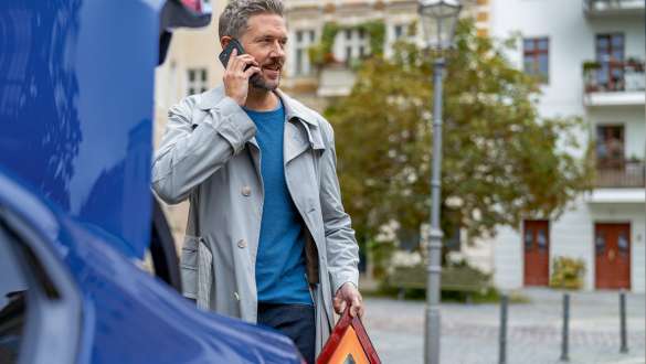 Muškarac stoji pokraj BMW-a Muškarac stoji pokraj BMW-a s pametnim telefonom