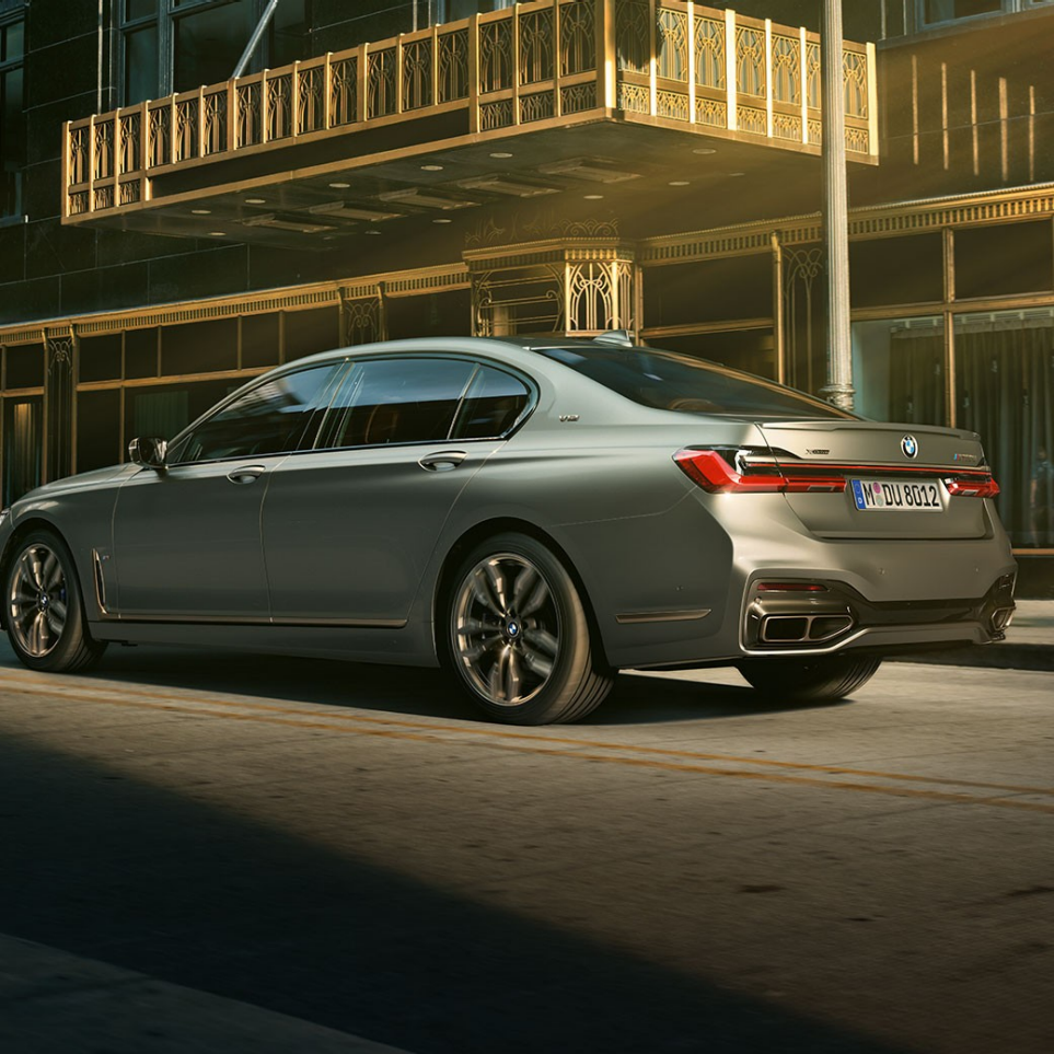 BMW M760Li xDrive s V12 motorom BMW M760Li xDrive stoji u bočnom stražnjem prikazu ispred nebodera u urbanom okruženju