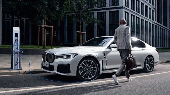 BMW 745e limuzina plug-in hybrid G11 G12 Mineral White tročetvrtinski pogled za vrijeme punjenja BMW 745e limuzina plug-in hybrid G11 G12 Mineral White tročetvrtinski pogled sa modelom
