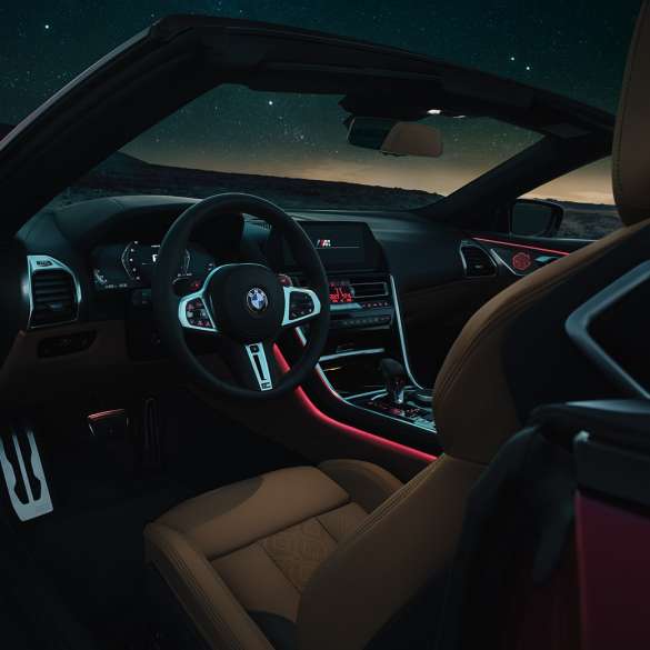 BMW M8 Competition Cabrio, kokpit. BMW M8 Competition Cabrio, kokpit noću s M kožnim upravljačem i crvenim ambijentalnim svjetlom.