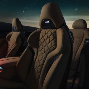M Sport sjedala u 'Merino' koži. BMW M8 Competition Cabrio sa spuštenim mekim krovom pod zvjezdanim nebom, unutrašnjost s M Sport sjedalima u 'Merino' koži i crvenim ambijentalnim svjetlom.