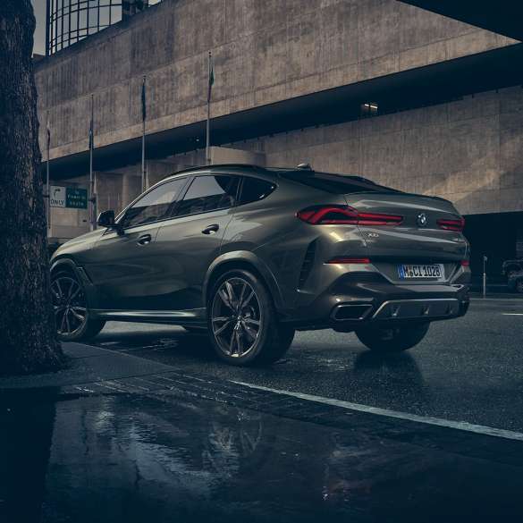 BMW X6 vanjština. BMW X6 iz stražnje tro-četvrtinske perspektive ispred urbanog okruženja.