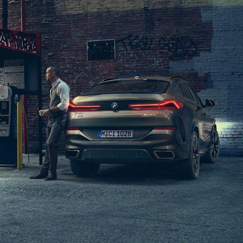 Stražnji kraj BMW-a X6. Perspektiva stražnjeg kraja BMW-a X6 ispred urbanog okruženja.