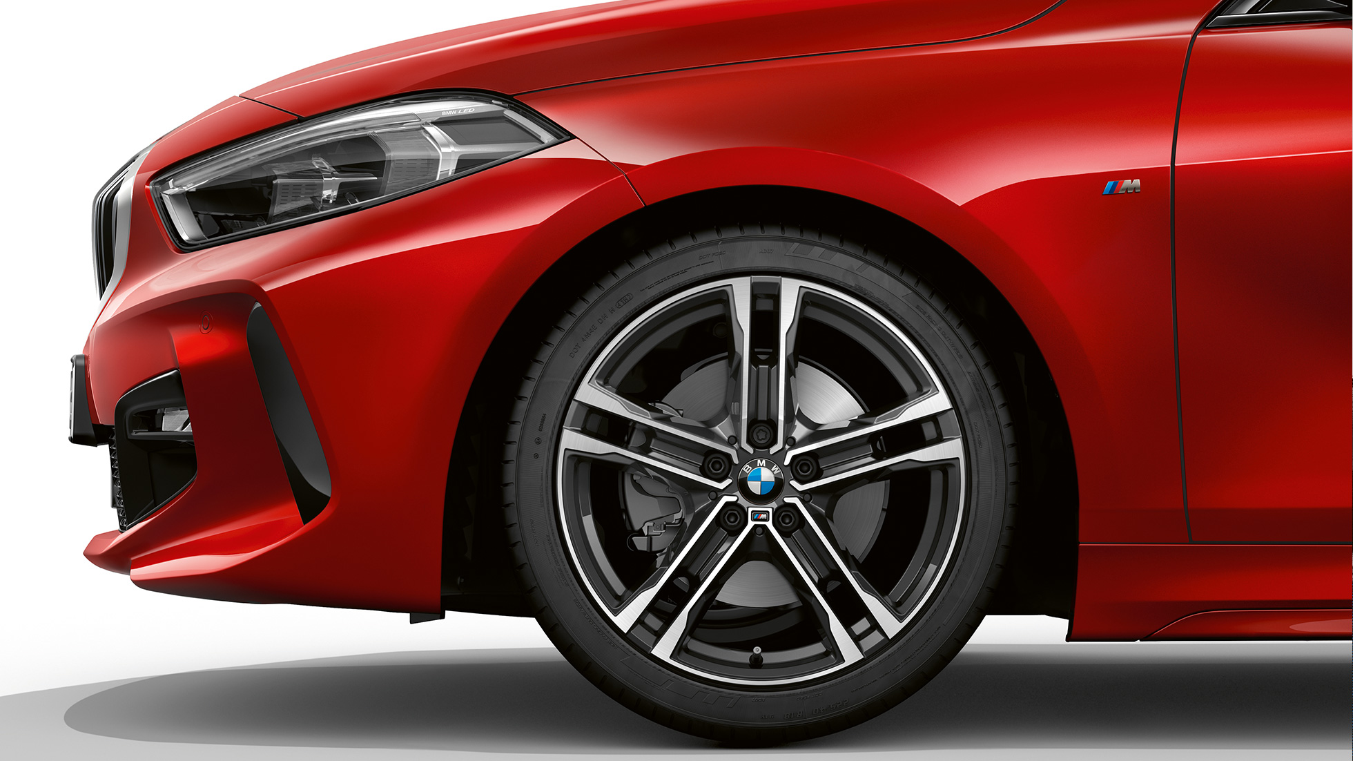 BMW serije 1 Model M Sport, bočni prikaz prednjeg kraja. BMW serije 1 Model M Sport u Melbourne Red metalik boji, bočni prikaz prednjeg kraja s 17" M lakometalnim kotačima Double-spoke 550 M Bicolour.