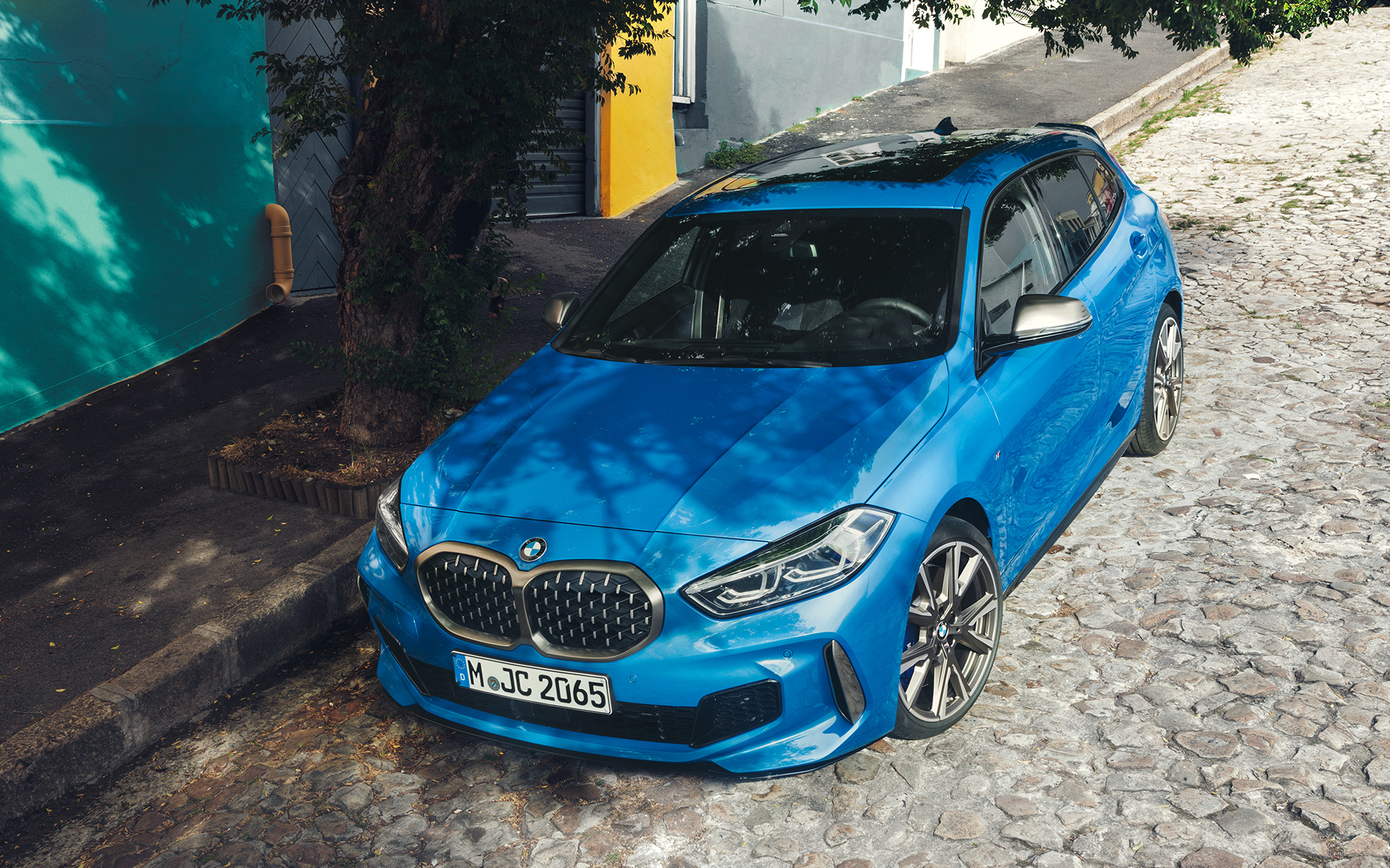 BMW serije 1 M135i F40 uz cestu BMW serije 1 M135i F40 Misano Blue metalik, tročetvrtinski prednji prikaz, parkiran uz cestu iz ptičje perspektive