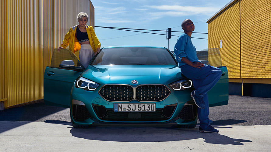 BMW serije 2 Gran Coupé F44, pogled sprijeda BMW serije 2 Gran Coupé F44 Snapper Rocks Blue, pogled sprijeda sa otvorenim vratima i dvoje ljudi u vozilu