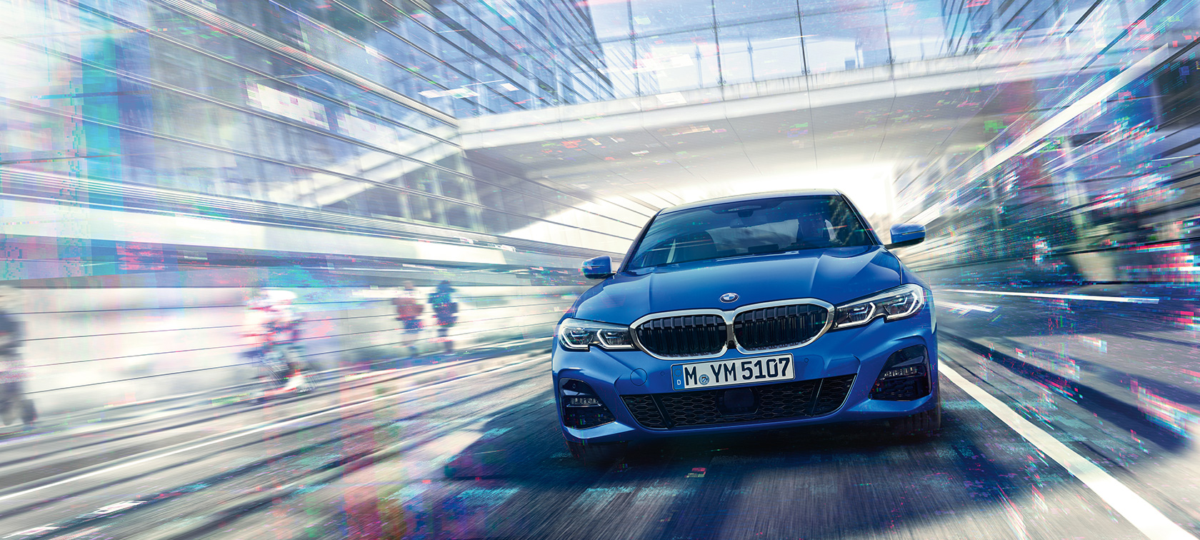 BMW serije 3 Limuzina, prednji prikaz. Prednji prikaz BMW-a serije 3 Limuzine u vožnji po danu ispod staklene zgrade.