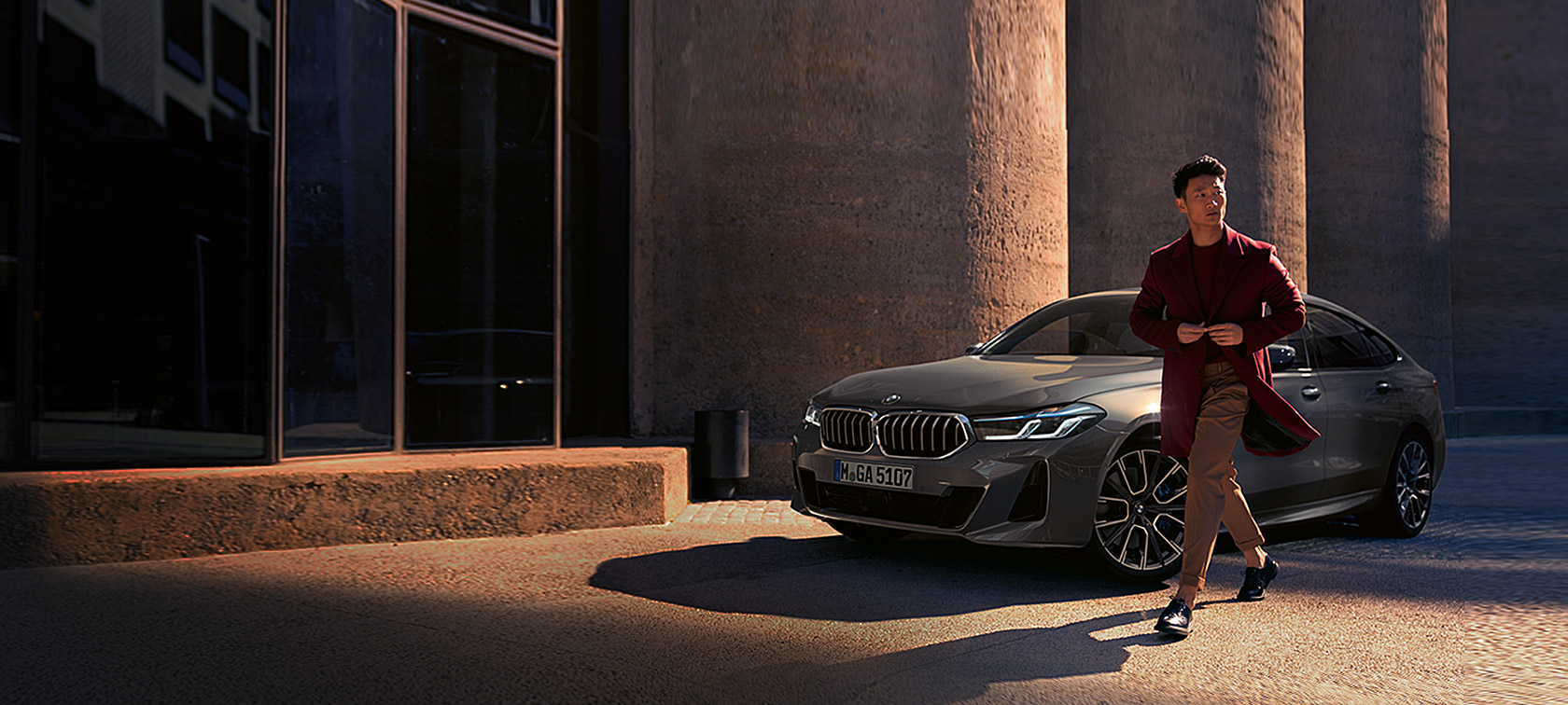 BMW serije 6 Gran Turismo 640i xDrive G32 2020 Bernina Grey muškarac ispred BMW-a tročetvrtinski pogled u mirovanju