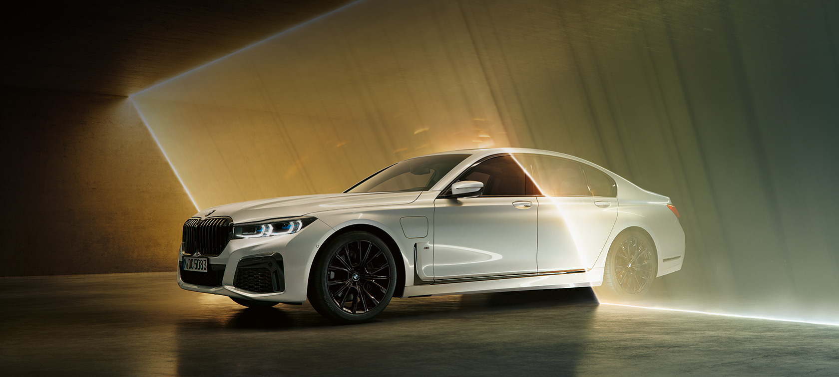 BMW serije 7 Limuzina, bijela, tročetvrtinski prednji prikaz BMW serije 7 Limuzina: bijeli BMW u tročetvrtinskom prednjem prikazu okružen svjetlosnim snopom