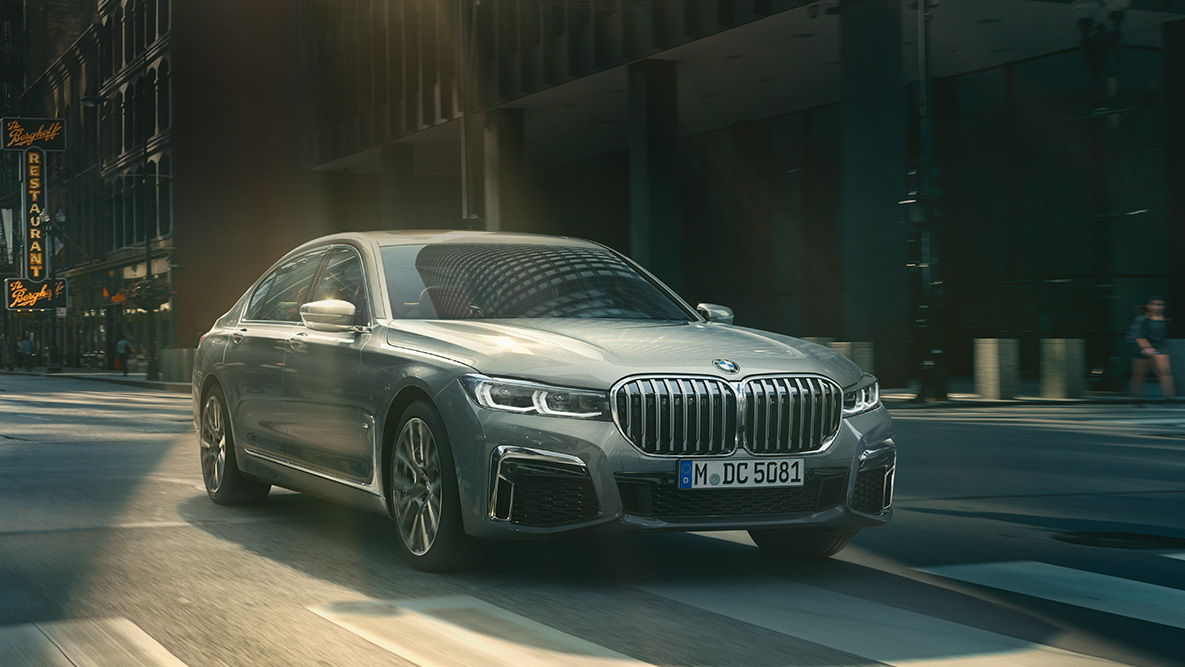 Opcija Driving Assistant Professional BMW-a serije 7 Limuzina Driving Assistant Professional: tročetvrtinski prednji prikaz BMW-a serije 7 Limuzina u vožnji ispred urbanog okruženja