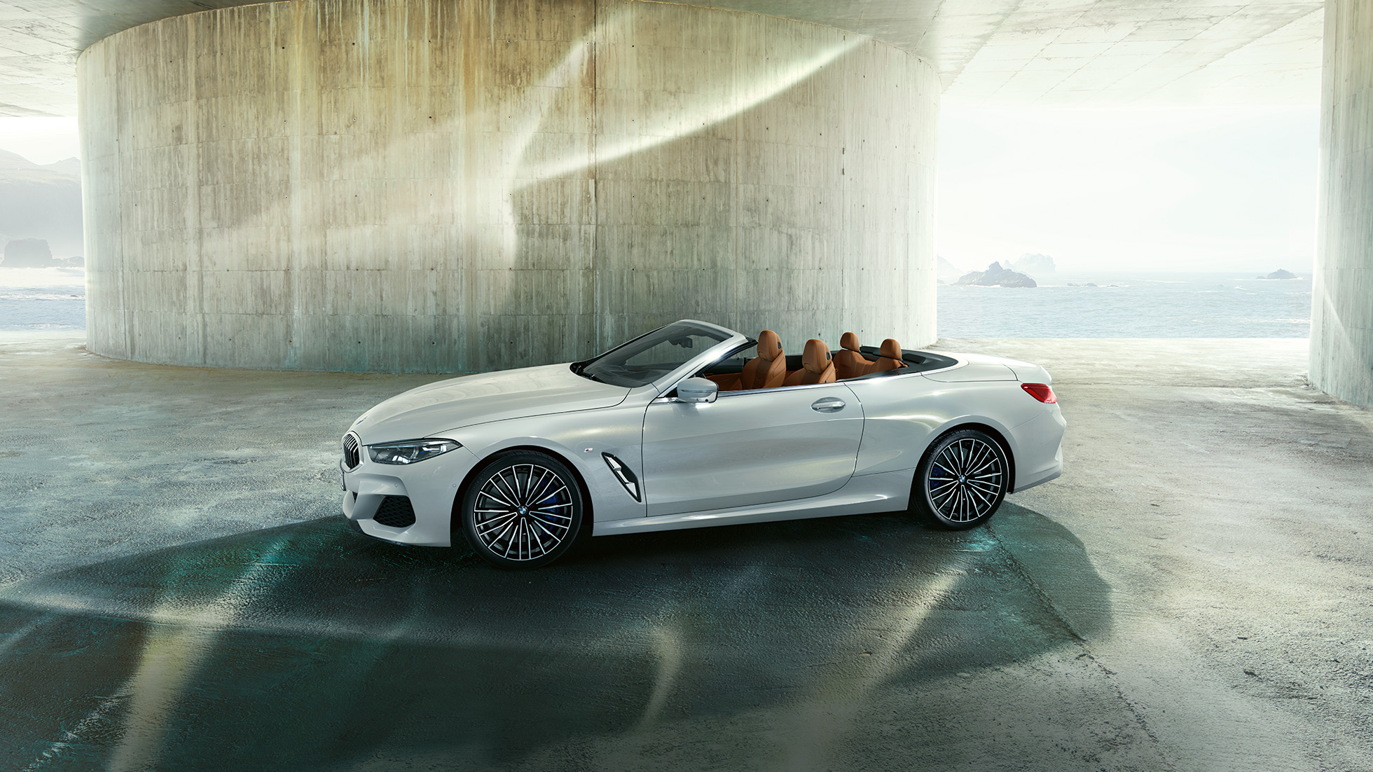 BMW M850i xDrive u Mineral White metalik boji, prikaz s bočne strane s otvorenim mekim krovom. BMW M850i xDrive u Mineral White metalik boji, prikaz s bočne strane s otvorenim mekim krovom.