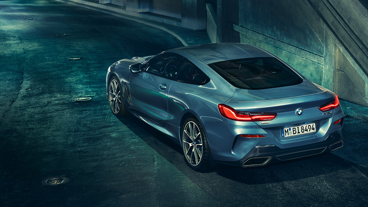 BMW serije 8 Coupé, tročetvrtinski prikaz stražnjeg kraja. Tročetvrtinski prikaz stražnjeg kraja BMW-a serije 8 Coupé noću ispred urbanog okruženja.