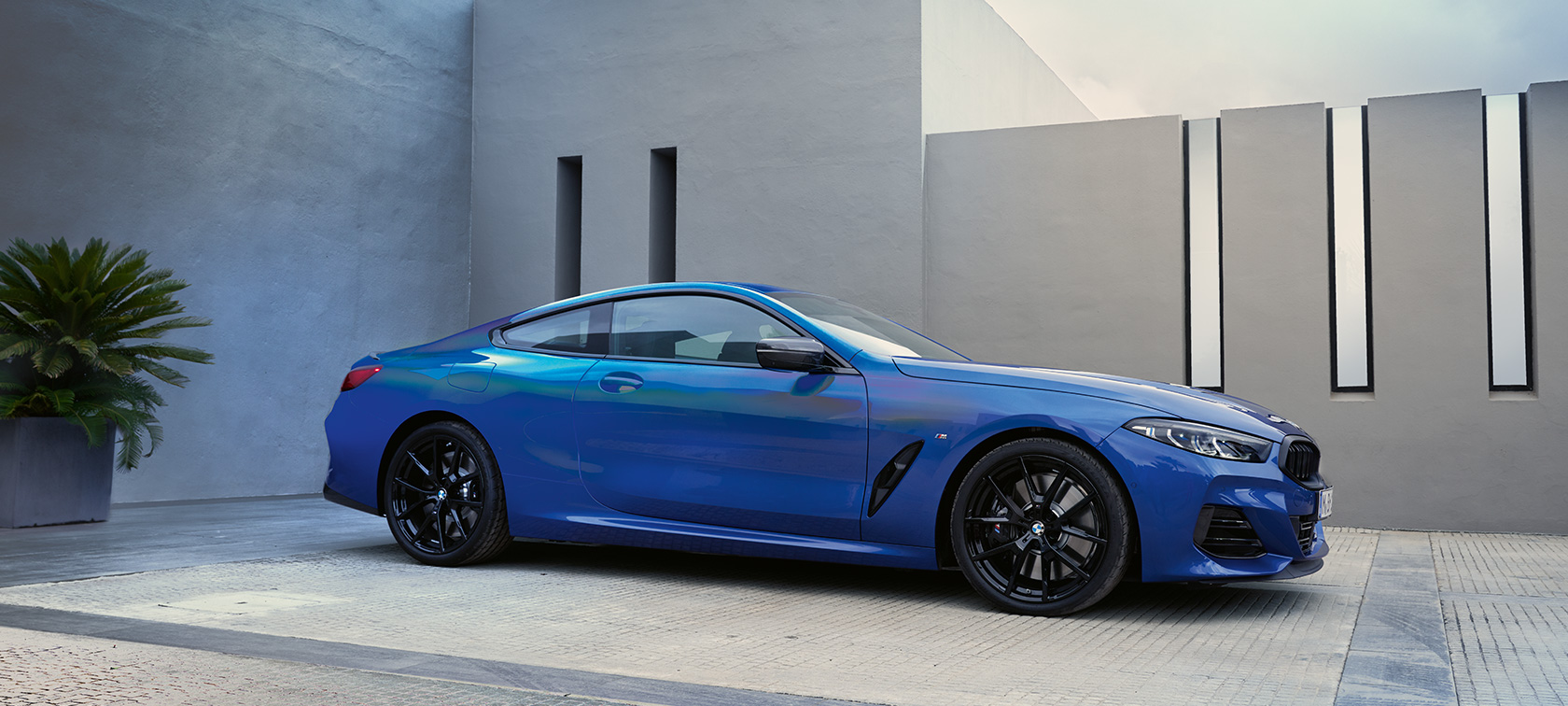 BMW serije 8 Coupé G15 LCI Facelift 2022 M Portimao Blue metalik Pogled s boka u mirovanju ispred kućnog zida