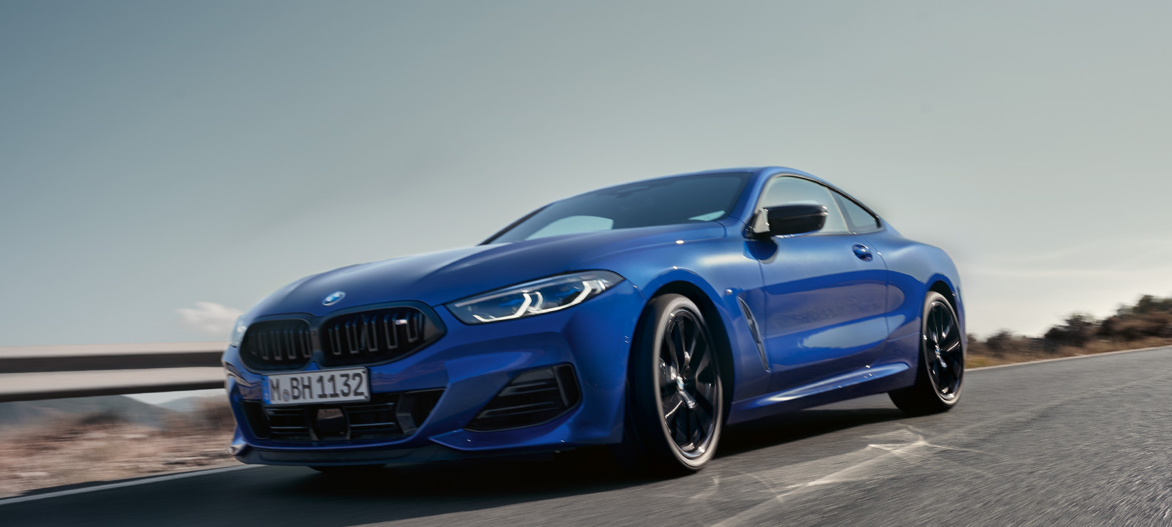 BMW serije 8 Coupé G15 LCI Facelift 2022 BMW M850i xDrive M Portimao blue metalik pogled sprijeda iz niskog kuta BMW serije 8 Coupé G15 LCI Facelift 2022 BMW M850i xDrive M Portimao blue metalik pogled sprijeda iz niskog kuta u vožnji seoskom cestom ispred planinskog krajolika u pozadini