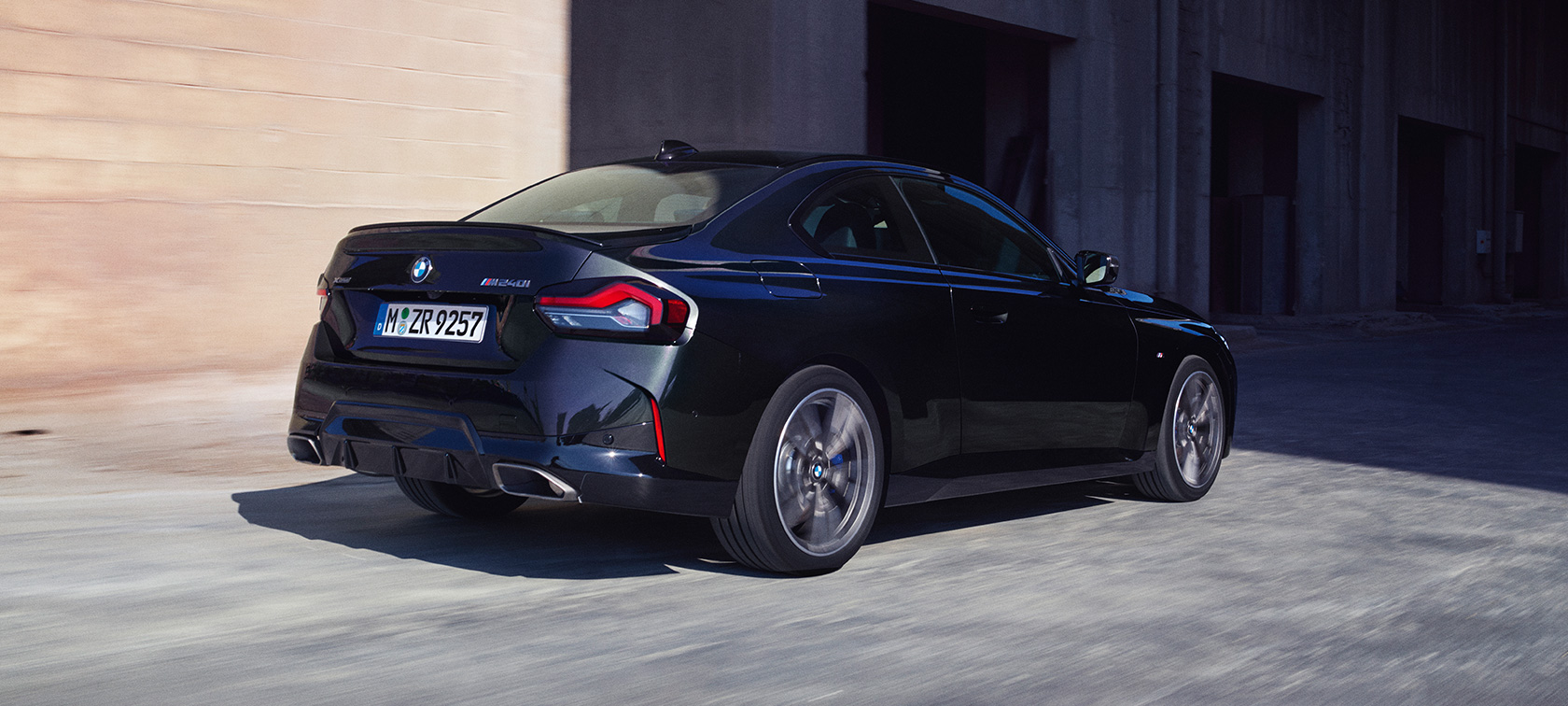Tročetvrtinski pogled straga BMW M240i xDrive Coupé G42 2021 BMW M240i xDrive Coupé G42 2021 Black Sapphire metalik tročetvrtinski pogled straga u vožnji