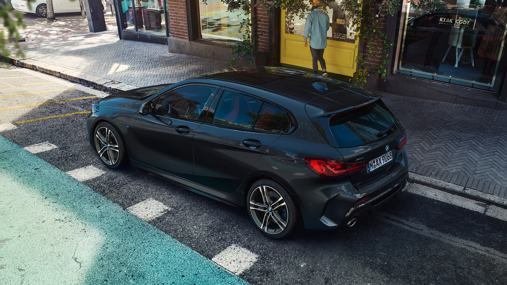 BMW M135i xDrive, parkiran. BMW M135i xDrive u Black Sapphire metalik boji, parkiran, ptičja perspektiva bočne strane.