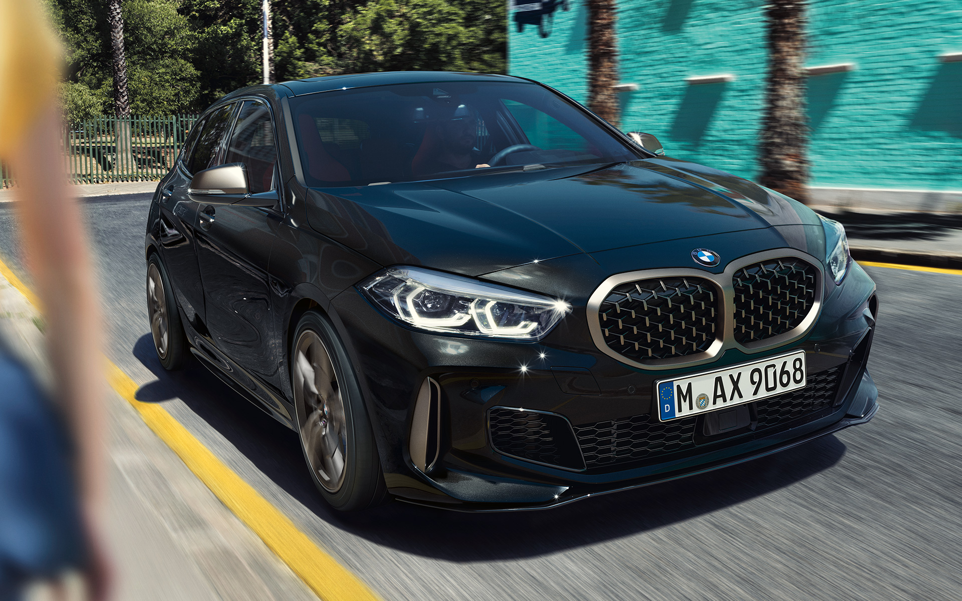 BMW M135i xDrive (F40) u Black Sapphire metalik, tročetvrtinski pogled sprijeda u vožnji