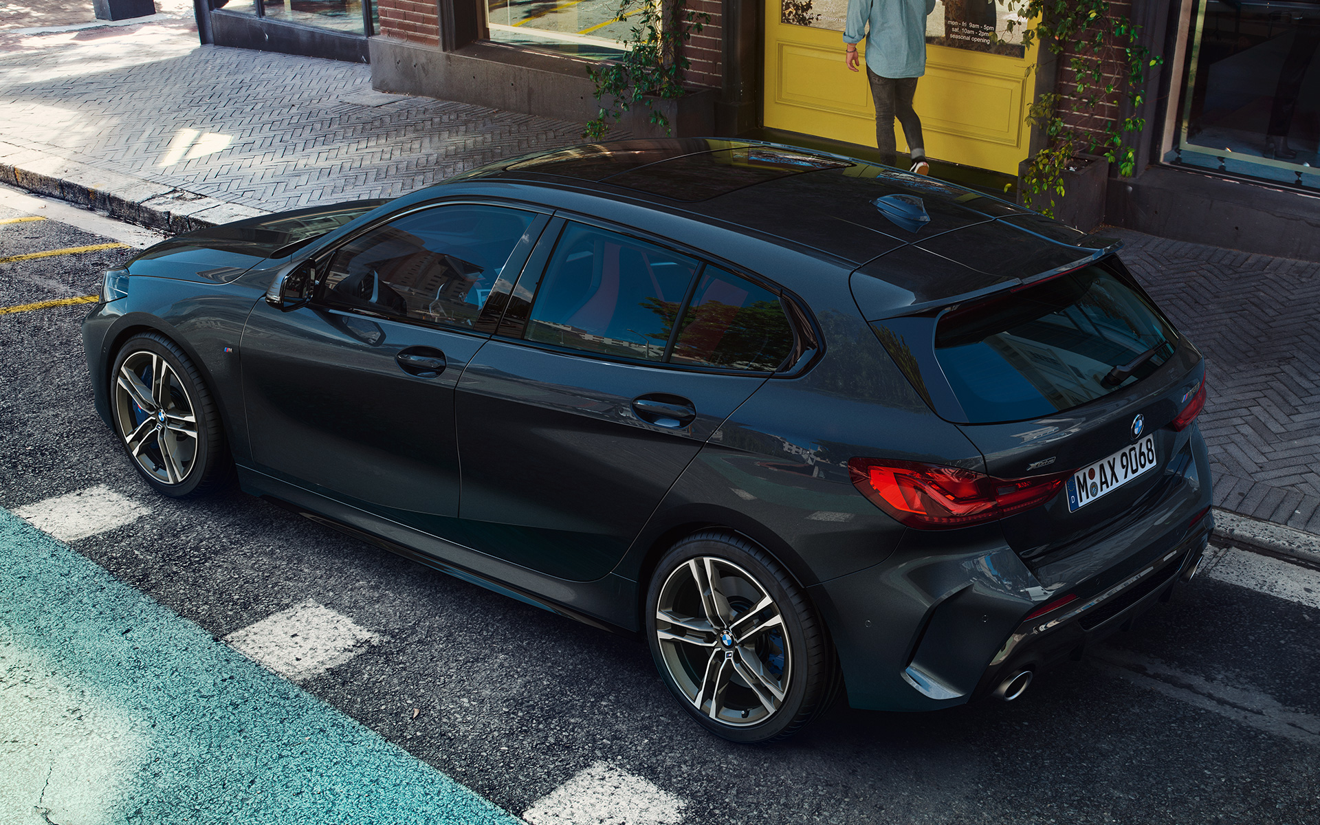 BMW M135i xDrive (F40) u Black Sapphire metalik na parkingu, pogled s visoka na bočnu stranu 