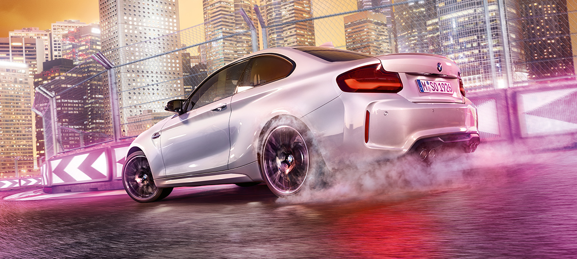 BMW M2 Competition ubrzava Bijeli model BMW M2 Competition na trkaćoj stazi ispred noćnog horizonta.