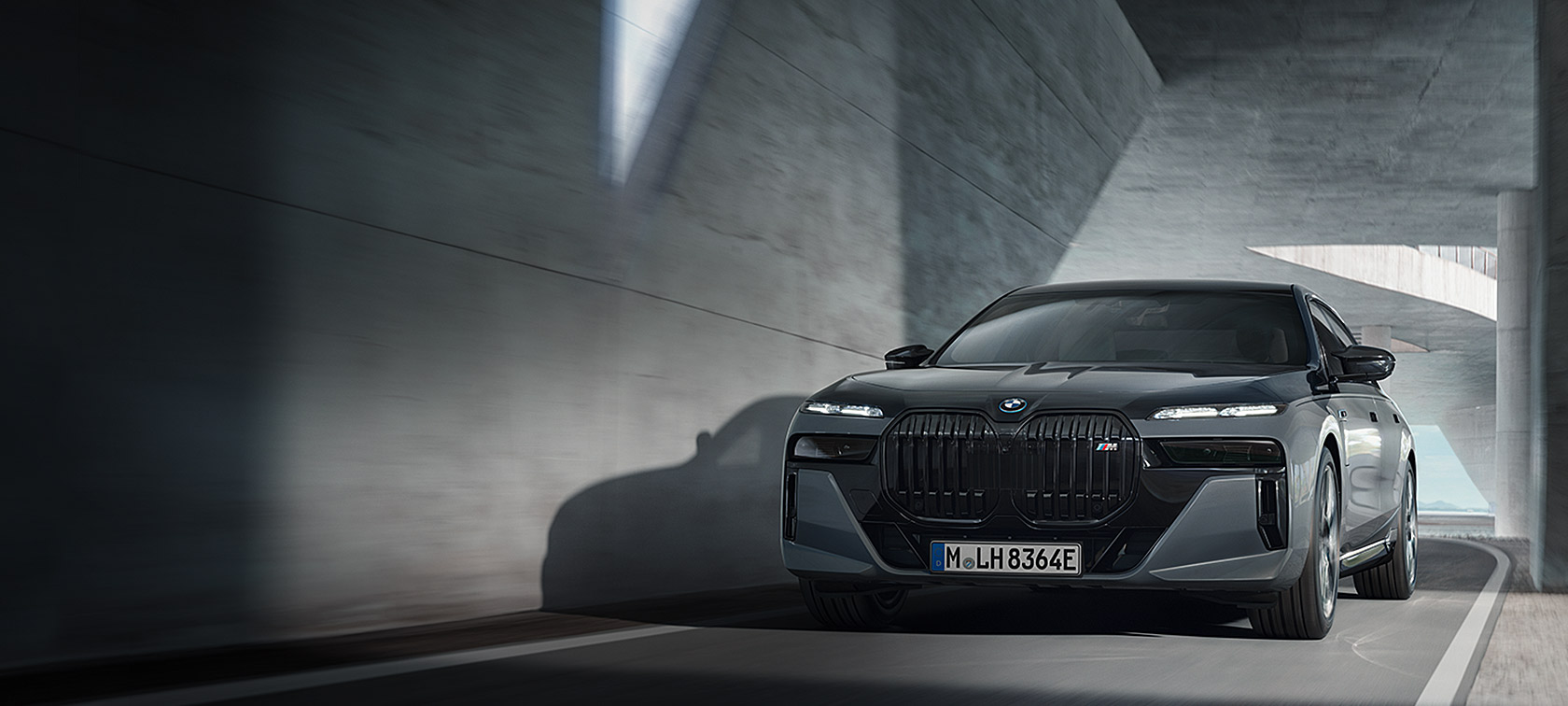 BMW M760e xDrive Limuzina G70 M Performance paket BMW Individual dvotonska Black Sapphire metalik boja BMW Individual Dravite Grey metalik tročetvrtinski prednji prikaz u vožnji na cesti