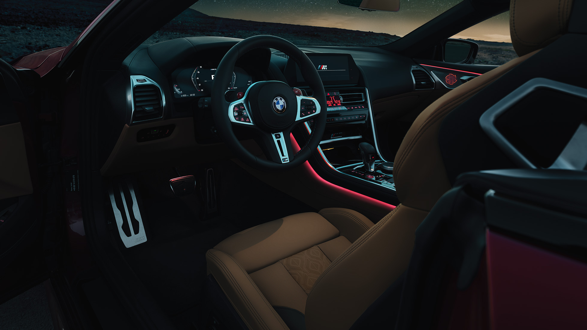 BMW M8 Competition Cabrio, kokpit. BMW M8 Competition Cabrio, kokpit noću s M kožnim upravljačem i crvenim ambijentalnim svjetlom.