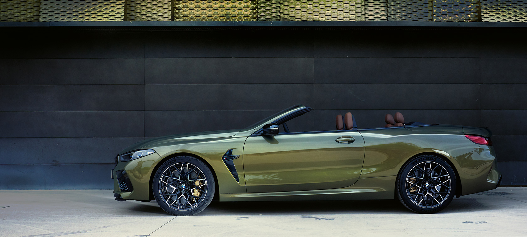 BMW M8 Competition Cabrio F91 LCI Facelift 2022 pogled s boka u mirovanju BMW M8 Competition Cabrio F91 LCI Facelift 2022 BMW Individual Brass metalik pogled s boka u mirovanju sa otvorenim vratima i ženskim modelom