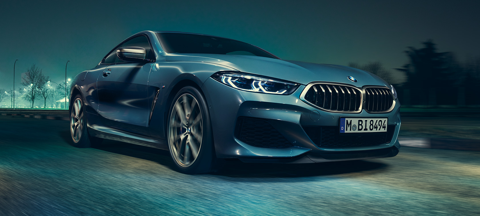 BMW M850i xDrive Coupé, tročetvrtinski prednji pogled. BMW M850i xDrive Coupé u Barcelona Blue metalik u vožnji, tročetvrtinski prednji pogled.