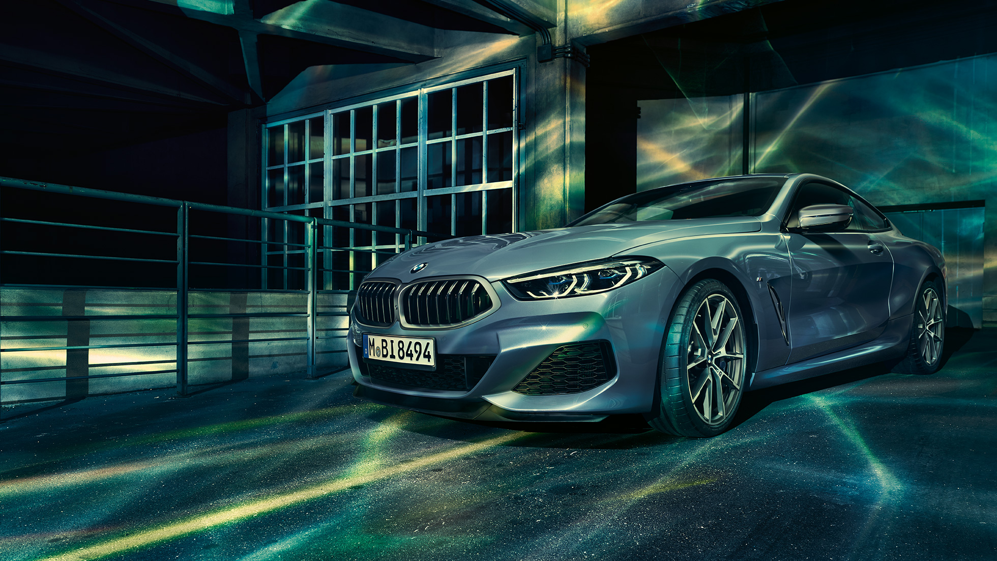 BMW M850i xDrive Coupé, tročetvrtinski prednji pogled. BMW M850i xDrive Coupé u Barcelona Blue metalik, tročetvrtinski prednji pogled ispred građevine.