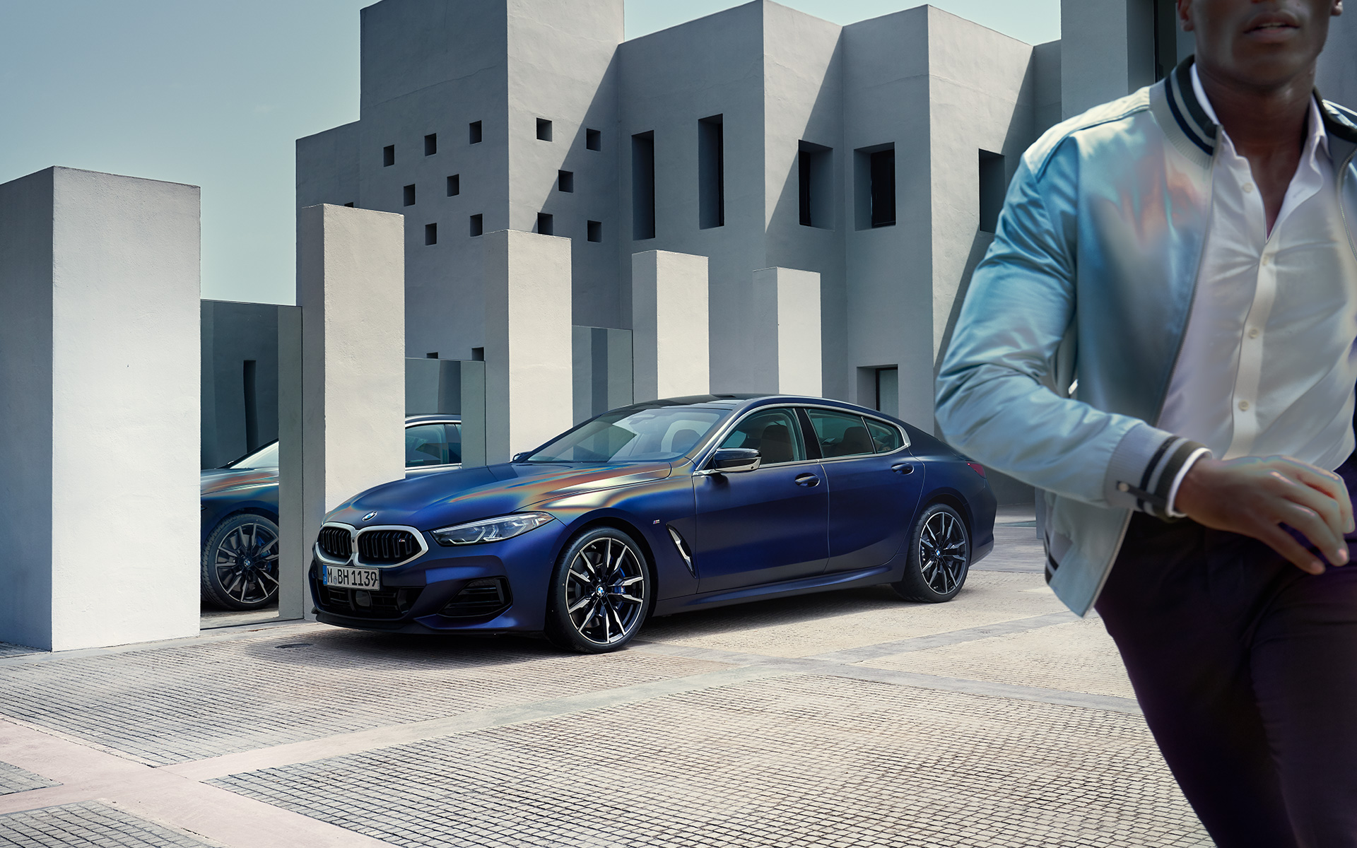Tročetvrtinski pogled sprijeda BMW M850i xDrive Gran Coupé F93 LCI Facelift 2022 BMW M850i xDrive Gran Coupé F93 LCI Facelift 2022 BMW Individual Frozen Tanzanite Blue metalik tročetvrtinski pogled sprijeda u mirovanju sa muškim modelom u prvom planu