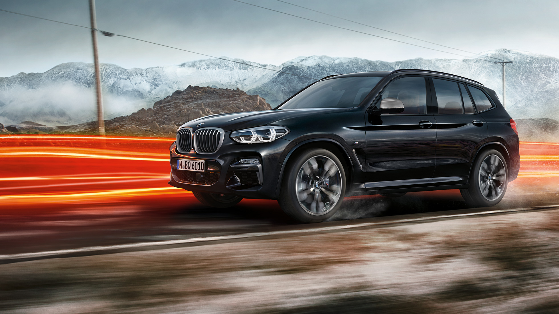 BMW X3 M40i i BMW X3 M40d, bočni prikaz. BMW X3 M40i i BMW X3 M40d u Black Sapphire metalik boji, u vožnji, vanjština, bočni prikaz ispred planinske pozadine sa svijetlosnim trakama.