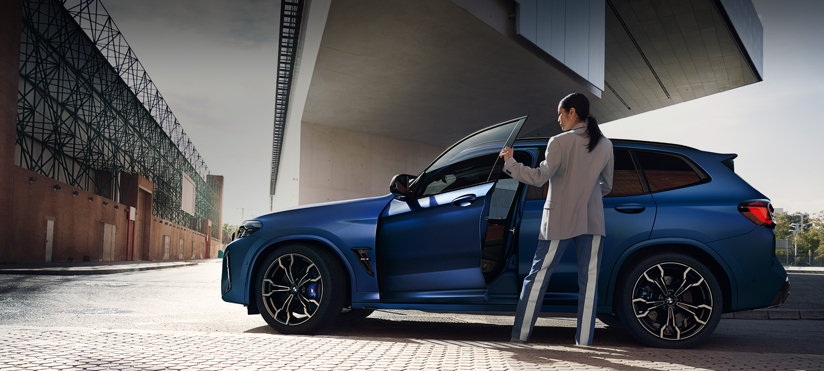 BMW X3 M Competition F97 LCI Facelift 2021 pogled s boka u mirovanju BMW X3 M Competition F97 LCI Facelift 2021 BMW Individual Frozen Portimao Blue metalik pogled s boka u mirovanju sa otvorenim vratima i ženskim modelom