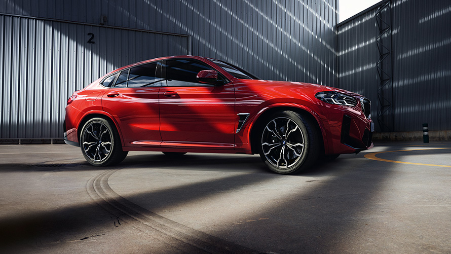 BMW X4 M F98 LCI Facelift 2021 Toronto Red metalik pogled s boka ispred industrijske zgrade