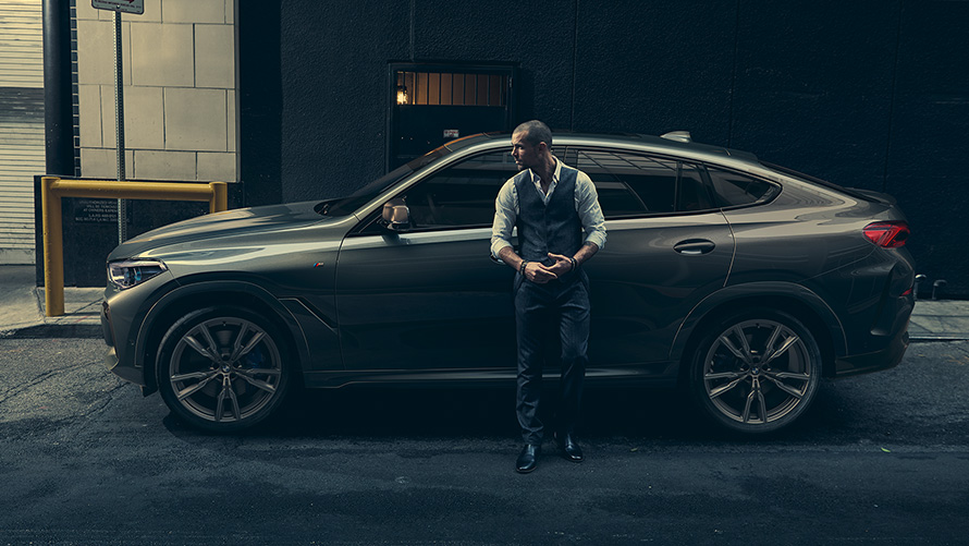 Mu&scaron;karac se naginje BMW X6 M50i iz bočne perspektive ispred urbane sredine G06 2018 SUV