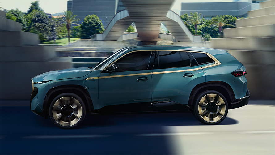 BMW XM G09 vanjština bočni pogled u vožnji traka night gold