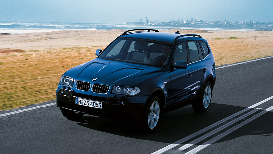 Tročetvrtinski prikaz prednjeg kraja BMW-a X3 E83 prve generacije u vožnji na ulici BMW serije X; Tročetvrtinski prikaz prednjeg kraja BMW-a X3 E83 prve generacije u vožnji na ulici