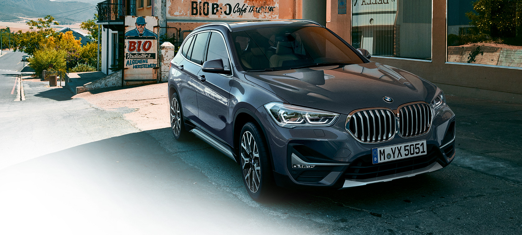 BMW X1, tročetvrtinski prednji prikaz. BMW X1, tročetvrtinski prednji prikaz parkiranog automobile ispred urbane sredine.