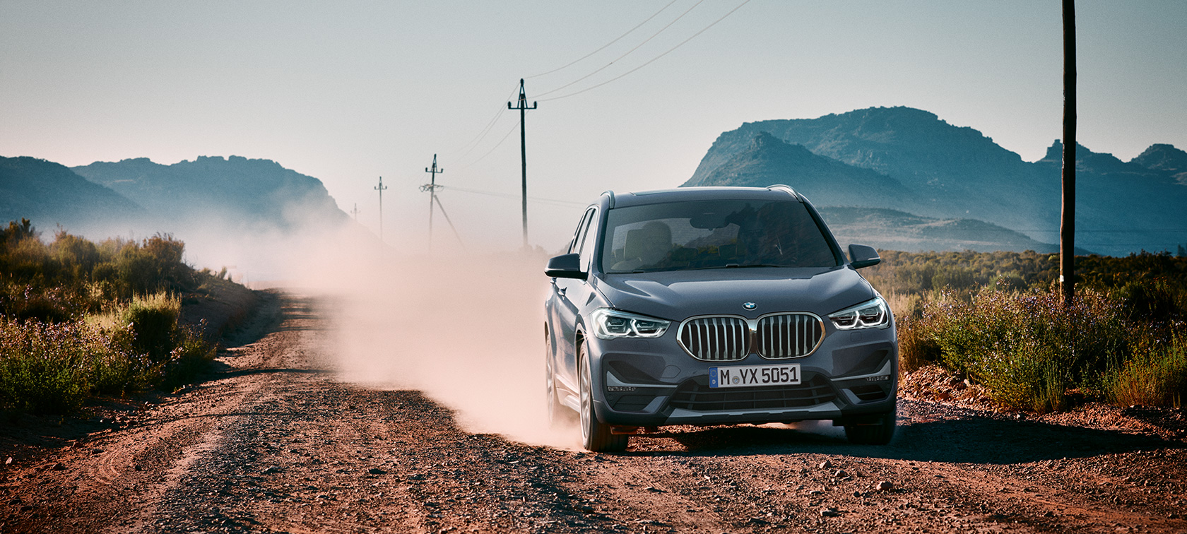 BMW X1, tročetvrinski stražnji prikaz. BMW X1, tročetvrinski stražnji prikaz vožnje kroz planine.
