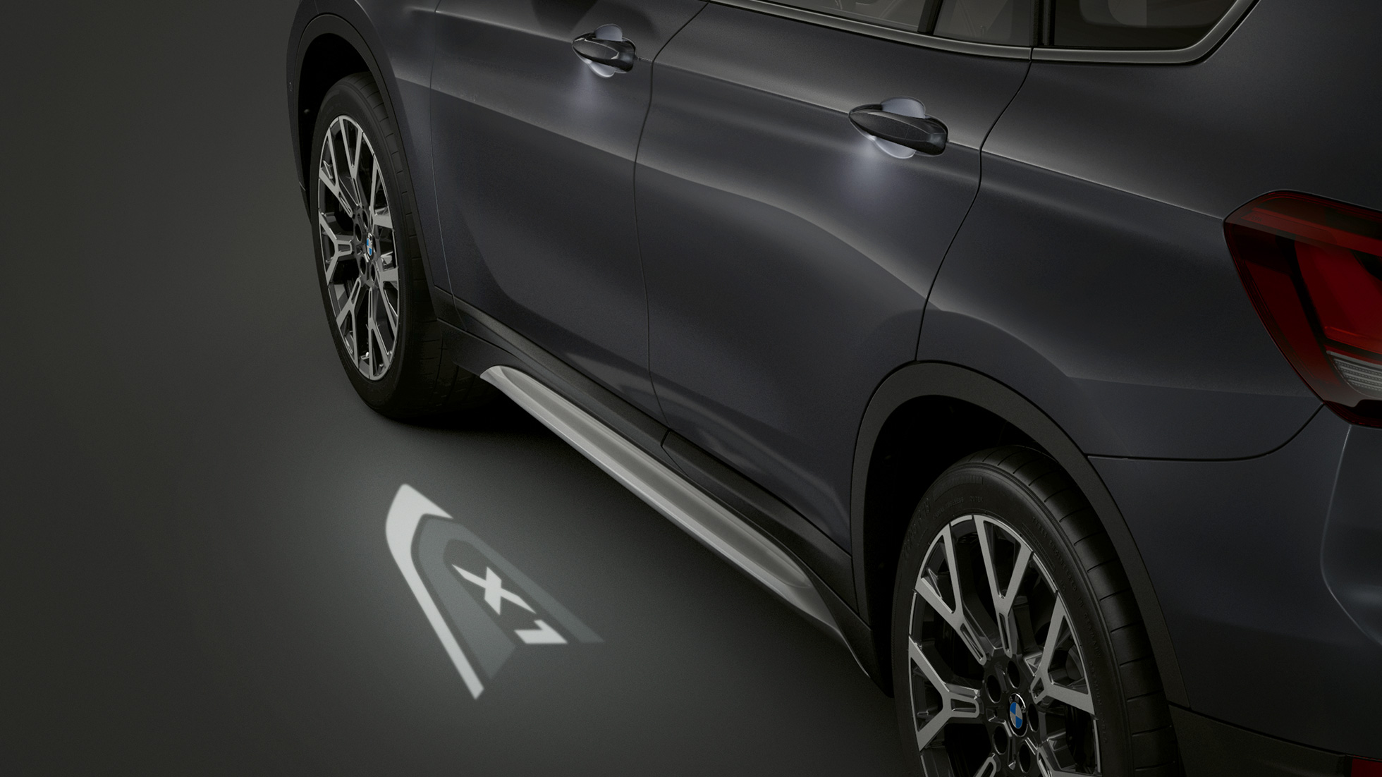 BMW X1, LED-projekcija “X1”. BMW X1, bočni prikaz sa fokusom na LED-projekciju “X1”.