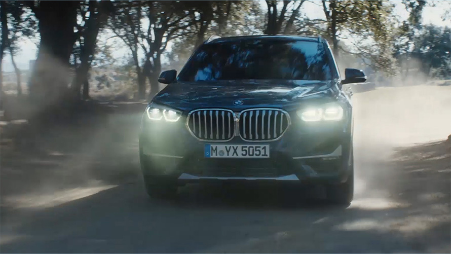 BMW X1 F48 LCI tročetvrtinski pogled sprijeda BMW X1 F48 LCI tročetvrtinski pogled sprijeda u vožnji ispred prirodnog krajolika