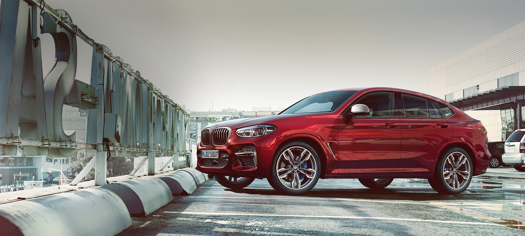 Bočni pogled na parkingu BMW X4 BMW X4 M40i G02 2018 Flamenco crvena sa briljantnim efektom bočni pogled na parkirnom mjestu