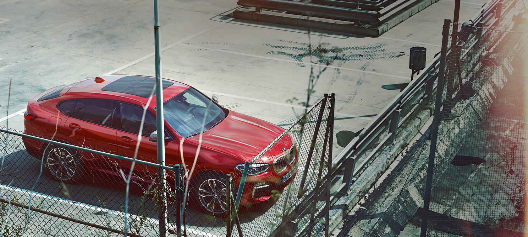 BMW X4 parkiran BMW X4 G02 2018 Flamenco Red s briljantnim efektom parkiran na parkirnom mjestu iz ptičje perspektive