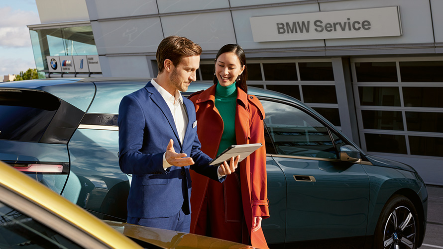 BMW Service muškarac i žena ispred BMW iX kod BMW servisnog partnera