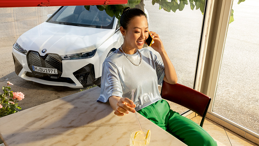 Zahtjevi proaktivne njege, pregled i održavanje Zahtjevi proaktivne njege, pregled i održavanje žena sjedi za stolom sa pametnim telefonom u ruci i BMW vozilom u pozadini